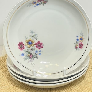 Peut inclure: Ensemble de trois bols en céramique blanche avec un motif floral. Les bols ont un bord doré et présentent un motif floral avec des fleurs roses, jaunes et bleues.