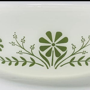 May include: White ceramic bowl with a green floral design. The design features a repeating pattern of stylized flowers and leaves.