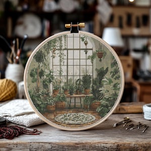 Könnte beinhalten: Ein Kreuzstich-Stickrahmen, der eine Gewächshausszene mit einem Fenster, Pflanzen und einem kleinen Teppich darstellt. Der Rahmen ist aus Holz und hat eine natürliche Oberfläche.