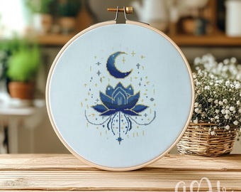 May include: A blue and gold embroidery hoop with a cross stitch design of a lotus flower with a crescent moon above it. The design is surrounded by small stars and dots.
