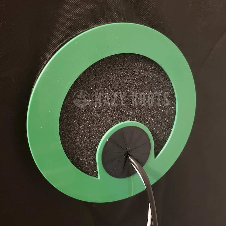 May include: A green circular grommet with a black foam insert and a black cable pass-through. The grommet is designed to protect cables from damage.