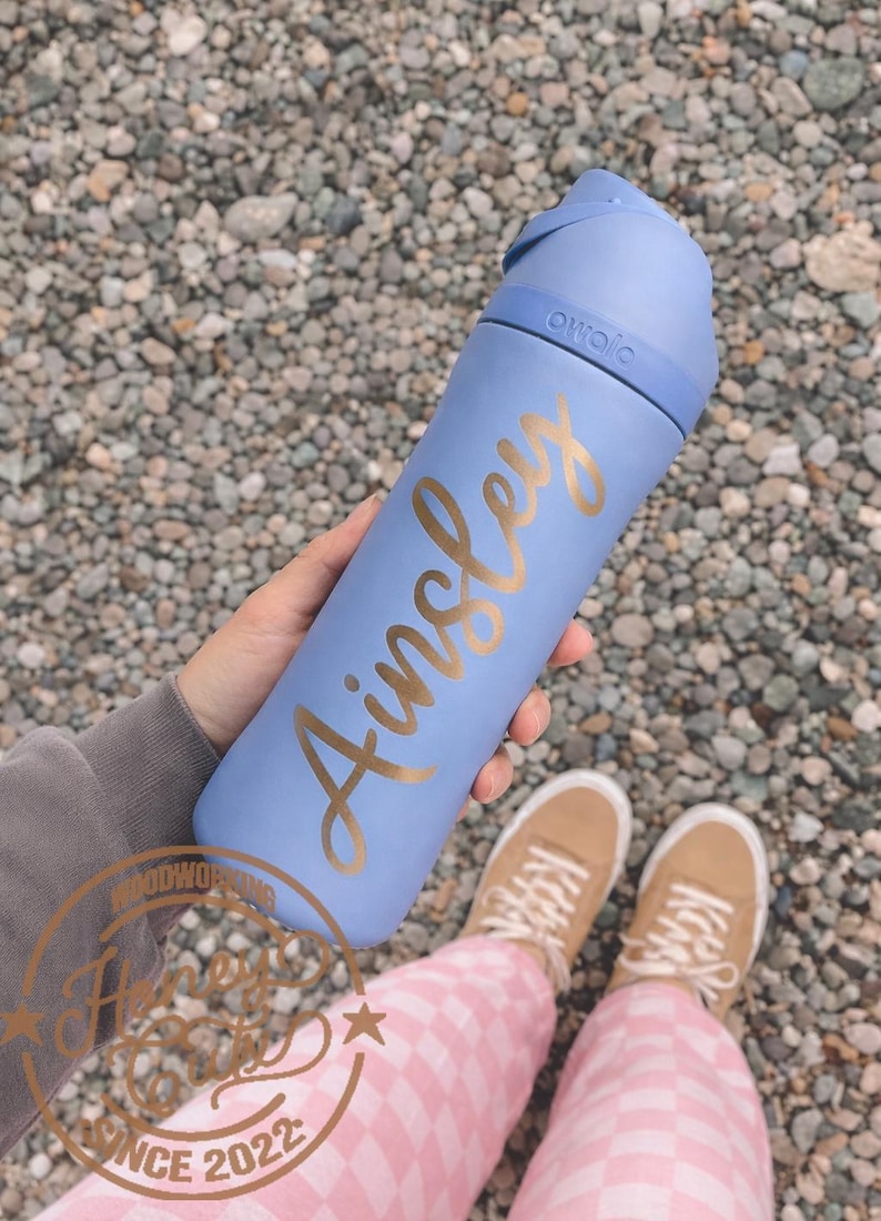 Op de afbeelding: Een witte keramische mok met een zwart handvat en de tekst "But First, Coffee" in een zwarte, vette letter. De mok staat op een houten oppervlak.