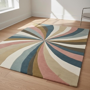 May include: A multi-coloured rug with a radial pattern. The rug has curved stripes in shades of pink, blue, beige, brown, and white. It's placed on a wooden floor. The room includes a window and a chair, creating a bright, inviting space.