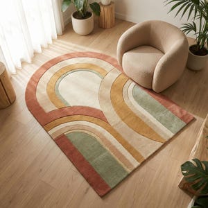 May include: A patterned rug with a rainbow design in shades of red, green, yellow, and cream. The rug is placed on a wooden floor. A beige chair and potted plants are visible in the background. The rug's design is arched.