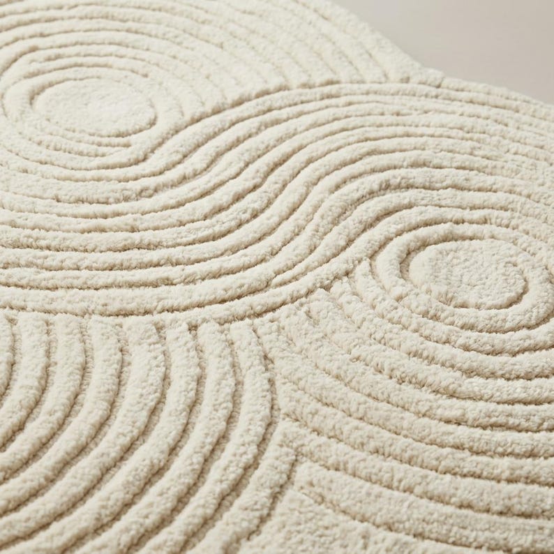 Close-up of soft wool tufted pile showing carved sculpted loop and cut texture with raised topographic ripple detailing in cream ivory