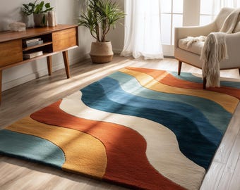May include: A rectangular area rug with a wavy pattern in shades of blue, orange, yellow, and white. The rug is placed on a hardwood floor, with a wooden cabinet, plants, and a chair in the background.