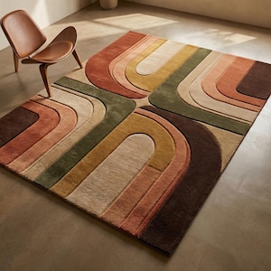 May include: A rectangular area rug with a retro design. The rug features curved, layered patterns in shades of brown, orange, green, and beige. A brown wooden chair is in the upper left corner. The rug is a floor covering.