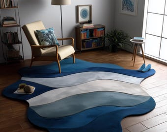 Puede incluir: Una alfombra grande y abstracta con un diseño ondulado en tonos azules y grises. La alfombra está colocada sobre un suelo de madera, con una silla y una mesa auxiliar en el fondo. La alfombra mide aproximadamente 213 cm por 152 cm.