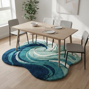 May include: A dining room set with a light wood table, four gray chairs, and a blue and white wave-patterned rug. The rug is a focal point, with swirling shades of blue and white. The table is set with plates, silverware, and a bowl.