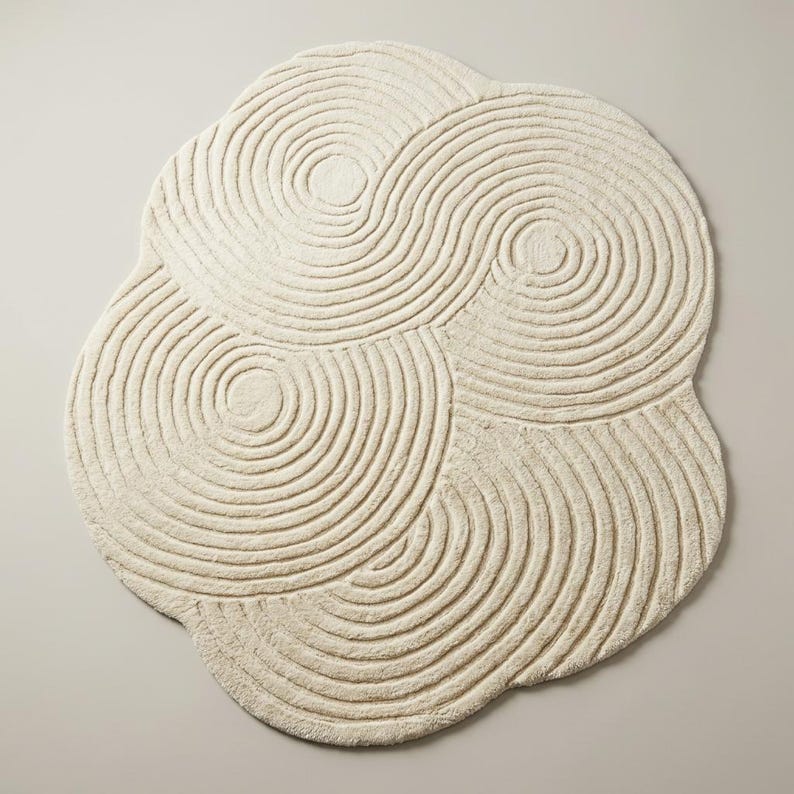 Modern sculpted hand tufted area rug with abstract curved line design and freeform shape placed on wooden flooring