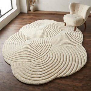 Hand tufted wool rug in organic irregular shape with carved abstract ripple pattern in ivory for modern minimalist living room décor