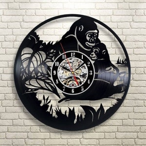 May include: Black vinyl record clock featuring a silhouette of a gorilla holding a baby gorilla. The clock face is white with black numbers and hands.