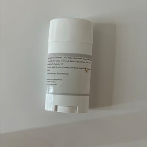 Puede incluir: Barra de desodorante blanca con una etiqueta que enumera los ingredientes, incluyendo aceite de coco, manteca de cacao, manteca de karit&eacute;, aceite de almendras dulces, &oacute;xido de zinc, arrurruz, arcilla caol&iacute;n, cera de abejas, aceite esencial de &aacute;rbol de t&eacute; y aceite de fragancia. La etiqueta tambi&eacute;n incluye instrucciones de uso y una advertencia para dejar de usar si se produce irritaci&oacute;n.