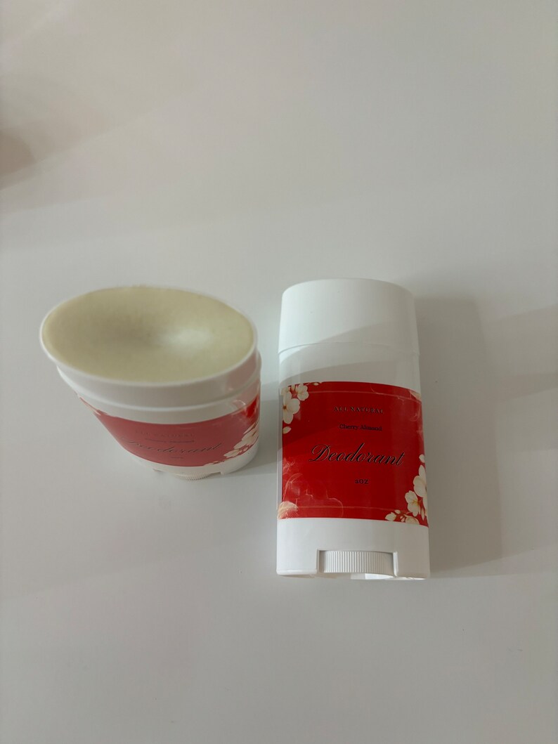 Puede incluir: Un stick de desodorante blanco con una etiqueta roja que dice "All Natural Cherry Almond Deodorant 3 oz". La etiqueta tiene un dise&ntilde;o floral con flores blancas sobre un fondo rojo.