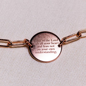 May include: A rose gold chain bracelet with a round charm that reads "Trust in the Lord with all your heart and lean not on your own understanding;"