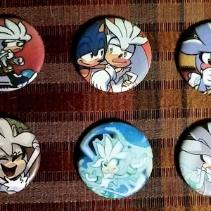 May include: Set of six round buttons featuring the character Silver the Hedgehog from the Sonic the Hedgehog video game series. Each button has a different image of Silver in various poses, with a red, blue, and white color scheme.