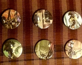 May include: Six round pinback buttons with various cartoon illustrations. The buttons feature images in shades of brown, black, green, and purple. The buttons are arranged on a striped brown and tan surface.