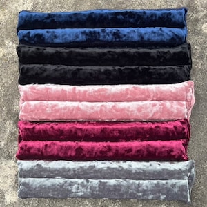 May include: Five velvet cushions in different colors, stacked on top of each other. The colors are navy blue, black, pink, burgundy, and gray.
