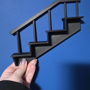 May include: A black 3D printed wall shelf shaped like a staircase with four shelves.