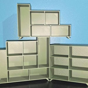 Puede incluir: Una estantería modular beige con múltiples estantes y compartimentos. La unidad está hecha de madera y tiene un diseño simple y moderno.