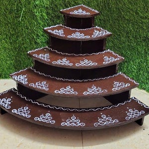 Peut inclure: Présentoir en bois marron à plusieurs niveaux avec des motifs décoratifs blancs. Le présentoir comporte plusieurs étagères incurvées, chacune ornée de motifs blancs complexes. Le présentoir est conçu pour présenter des articles.
