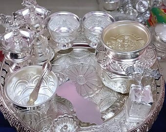 Puede incluir: Una bandeja de plata con una variedad de cuencos, tazas y otros artículos de plata. La bandeja está decorada con un intrincado diseño floral.