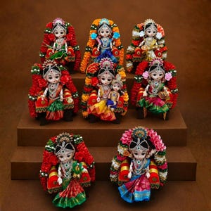 Puede incluir: Una colección de ocho pequeñas muñecas decorativas dispuestas en niveles escalonados. Cada muñeca presenta rasgos faciales detallados, joyas ornamentadas y ropa tradicional colorida, sentada dentro de un marco adornado con flores en tonos rojos, verdes y dorados.