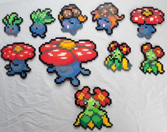 May include: A collection of eight pixel art figures of various Pokemon characters. The figures are made of colourful beads and feature characters like Bulbasaur, Oddish, and Venusaur.