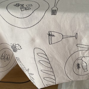 Hand embroidered imaginary dinner table cloth for 6 seattings , cutleries, food and drinks . Black on white and any colour