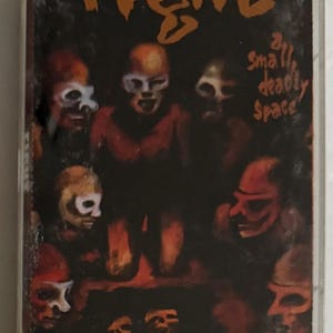 May include: A vintage cassette tape with the word "Fight" in orange, stylized lettering. The cover art features a dark, reddish-brown background with several skull-like figures. The text "all small deadly space" is also visible.