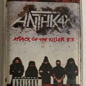 May include: A vintage cassette tape featuring the band Anthrax's album "Attack of the Killer B's." The cover art displays the band's logo and album title in white, with a red and white background. Below, five figures are depicted. A parental advisory warning is also visible.