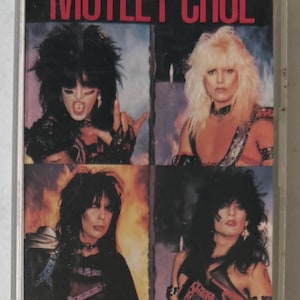May include: A vintage cassette tape of the band Mötley Crüe's album "Shout at the Devil." The cover features four band members with long hair and makeup against a black background. The band's name and album title are in red.