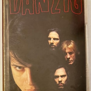May include: A vintage cassette tape for the album "Lucifuge" by the band Danzig. The cover features the band members' faces against a dark background, with the band name and album title in red lettering.