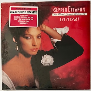 May include: A vinyl record cover featuring Gloria Estefan and Miami Sound Machine. The cover is red with a white flower and a photo of Gloria Estefan. The album title is "Let It Loose".