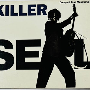 May include: A black and white image of a person holding a guitar. The person is silhouetted against a white background. The text "KILLER" and "SEAL" are in large, bold, black letters on the left side of the image. The text "Compact Disc Maxi-Single" is in smaller, black letters in the upper right corner of the image.