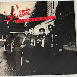 May include: Black and white album cover featuring three men in suits and sunglasses standing in front of a car. The album title is "LeVert The Big Throwdown".