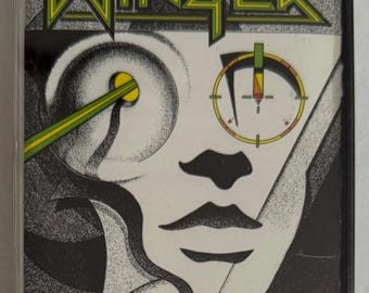 May include: A cassette tape featuring the band Winger. The cover art is a black and white illustration of a face with a target over one eye and a green laser beam. The band's name is in green and yellow.