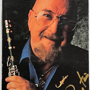 May include: A black and white VHS tape cover featuring a photo of Pete Fountain, a musician, holding a clarinet. The title of the tape is "Pete Fountain Swingin' Blues" and the cover includes his signature in gold lettering. The text "Digital Sound Series" is at the bottom of the cover.
