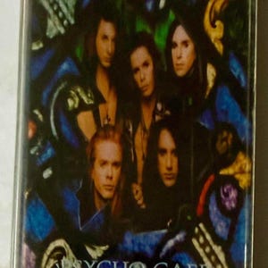 May include: A Bang Tango "Psycho Cafe" cassette tape. The cover features a group of six people with long hair, set against a stained-glass style background with blue and green hues. The band's name and album title are printed in white.