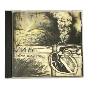 May include: A CD case with a black spine. The album art features a sketch of a heart and abstract landscape with the text "MAPS" and "YEAH YEAH YEAHS" in a handwritten style. The artwork is primarily black and white with yellow and gray accents.