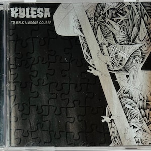 May include: A black and white CD case with the band name "KYLESA" and the album title "TO WALK A MIDDLE COURSE" printed on the front. The background is a black and white abstract design.