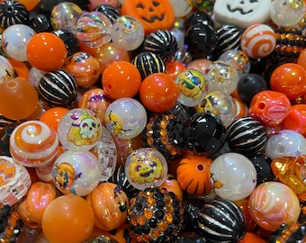 Può includere: Una collezione di perline assortite a tema Halloween in arancione, nero e bianco. Il mix include perline rotonde, sfaccettate e a righe, insieme a ciondoli con stampe di teschi, zucche e fantasmi con varie finiture lucide e opache.