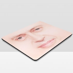 May include: A close-up of a person's face, drawn in pencil on a light pink background. The person is looking directly at the viewer with a slight smile.