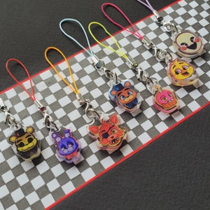 May include: A set of ten colorful keychains featuring cartoon characters from the popular video game Five Nights at Freddy's. Each keychain is made of clear plastic with a colorful character design. The keychains are attached to colorful strings.