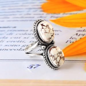 May include: A silver ring with two white and brown oval stones set in ornate silver settings.