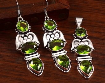 May include: A set of silver earrings and a pendant necklace with green gemstone accents. The earrings and pendant feature a decorative design with multiple stones.