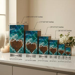 May include: A collection of wooden boxes with a heart-shaped design, ranging in size from 5" x 3" x 3" to 14" x 7.5" x 7.5". Each box features a blue and green wave pattern and the name "John Conner" engraved on the heart.
