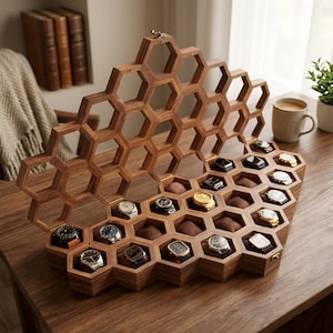 May include: A wooden watch display case featuring a honeycomb-inspired hexagonal grid design. The open lid reveals multiple individual compartments, each containing a wristwatch resting on a brown cushion, organised within the geometric wooden frame.