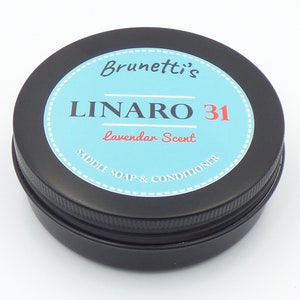 May include: A round, black tin of Brunetti's LINARO 31 saddle soap and conditioner with a lavender scent. The label is light blue with white dotted trim and text in black and red.
