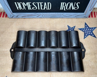 May include: A black cast iron gem pan with 10 individual molds. The pan is labeled "The Warner  Sliver Co. 1325" and "10 GEM PAN".